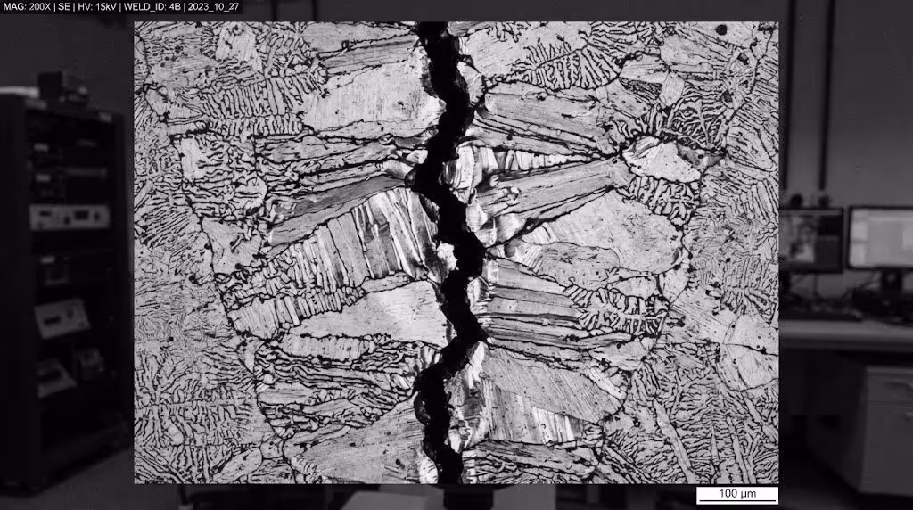 The microstructure of the centerline solidification cracks in steel welded parts: Under a 200x magnification, it is observed that the crystal boundaries are pulled apart, which is a typical characteristic of hot cracks.